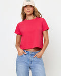 Front view of a model wearing the LSPACE All Day Top in pout, a cropped crew-neck tee with short sleeves, styled with a cream baseball cap and light wash jeans.