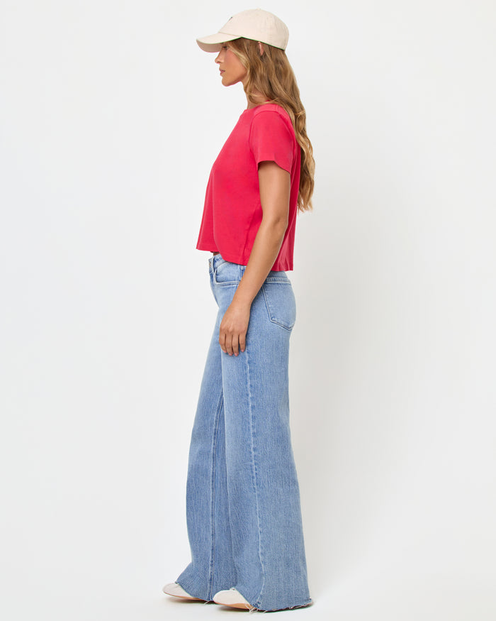 Side view of a model wearing the LSPACE All Day Top in pout, a cropped crew-neck tee with short sleeves, paired with light wash wide-leg jeans.