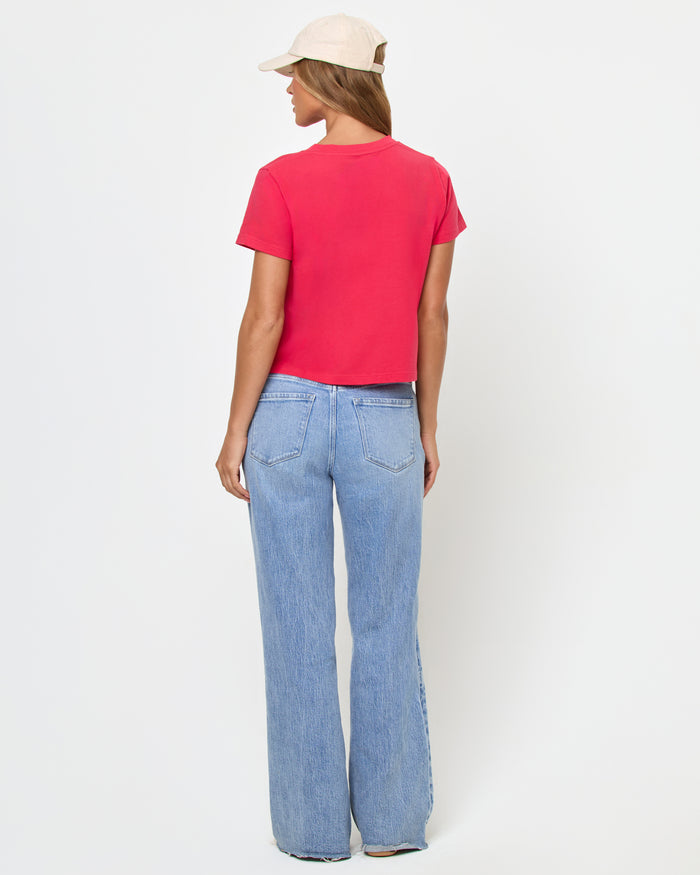 Back view of a model wearing the LSPACE All Day Top in pout, a cropped crew-neck tee with short sleeves, paired with light wash wide-leg jeans.