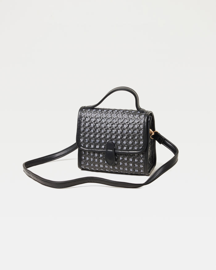 Off-model image of the Amelia Bag in black, a structured mini woven top-handle crossbody bag, with the crossbody strap extended.