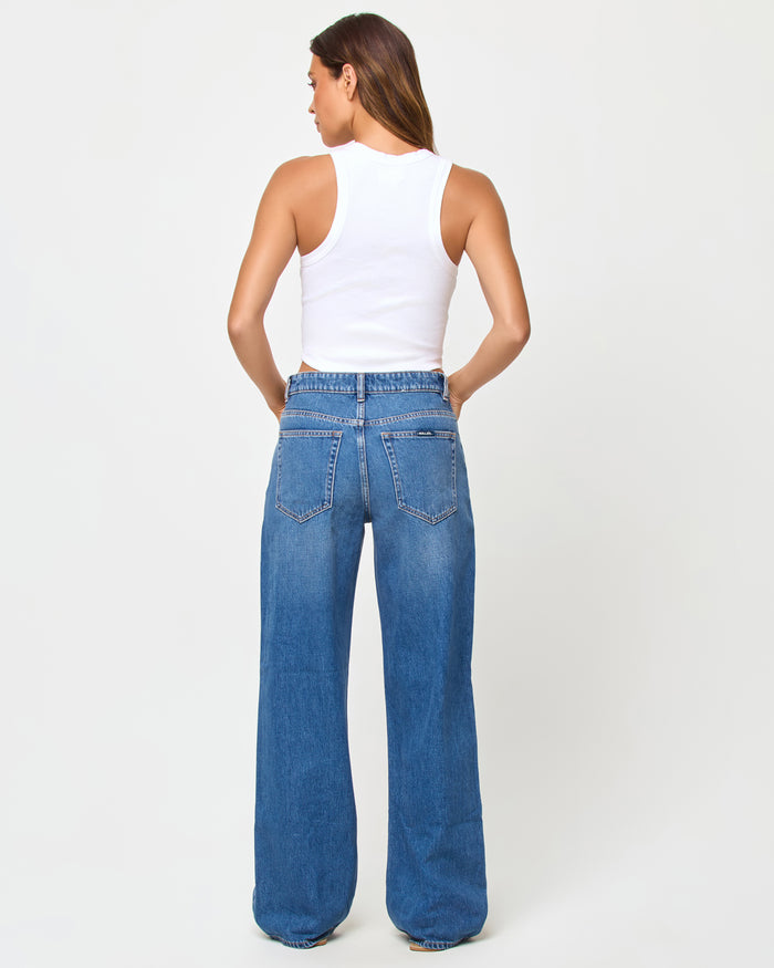 Back view of model wearing the LSPACE Ash Tank in papaya, a ribbed tank top in a warm orange papaya tone.
