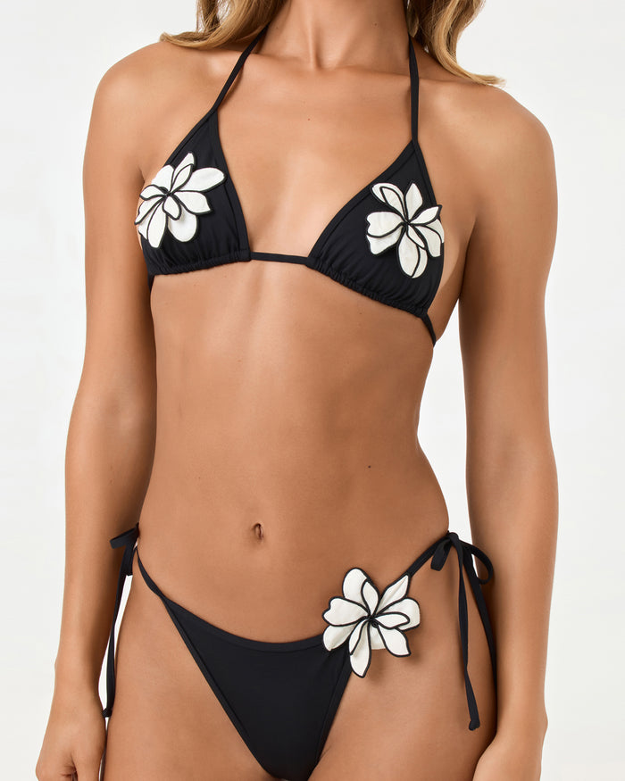 Close-up front view of a model wearing the LSPACE black Aspen Bikini Top, showing white floral appliqué detail.