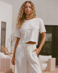 Lifestyle image of model wearing the LSPACE Core Top in cream-natural, a cropped short-sleeve top in cream.