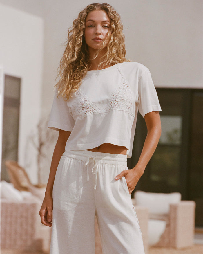 Lifestyle image of model wearing the LSPACE Core Top in cream-natural, a cropped short-sleeve top in cream.