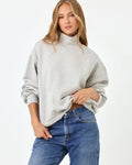 Front studio three-quarter torso view of the Crush Sweatshirt in Heather Gray, a heather gray oversized quarter-zip pullover sweatshirt with a mock neck, styled with blue denim jeans.