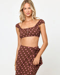 Front view of a model wearing the LSPACE Ever Top in alotta polka dot, a chocolate brown and pink polka dot crop top with cap sleeves and a square neckline, styled with the matching wrap skirt.