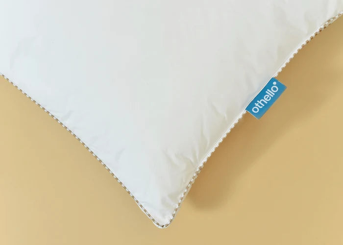 White filled pillow corner with blue othello tag and piped seam