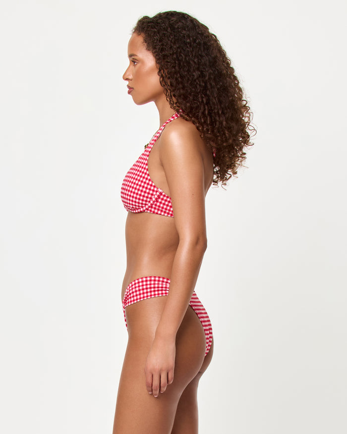 Side view of a model wearing the LSPACE lipstick red Isa Bikini Top and Dolce Bikini Bottom showing the halter neckline and gingham print silhouette.