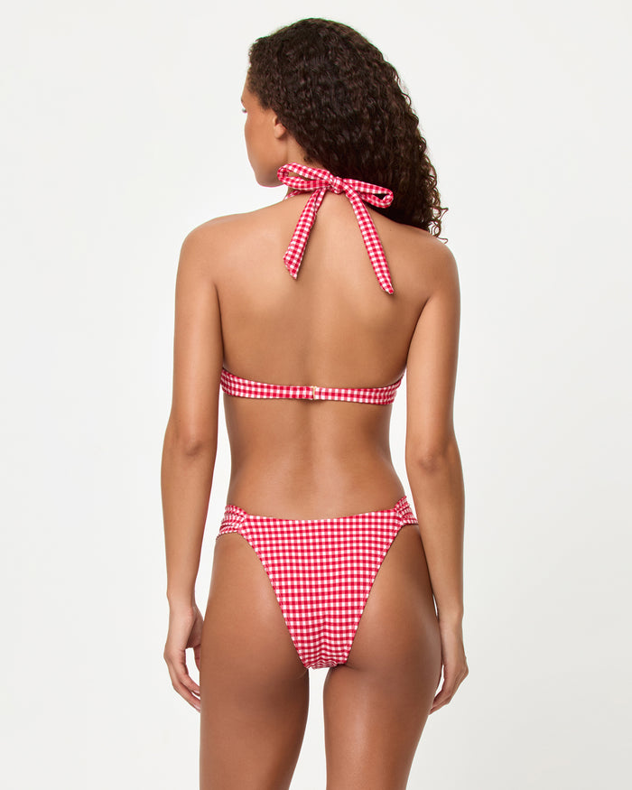 Back view of a model wearing the LSPACE lipstick red Isa Bikini Top and Dolce Bikini bottom showing the halter neck tie and band back closure in gingham print.