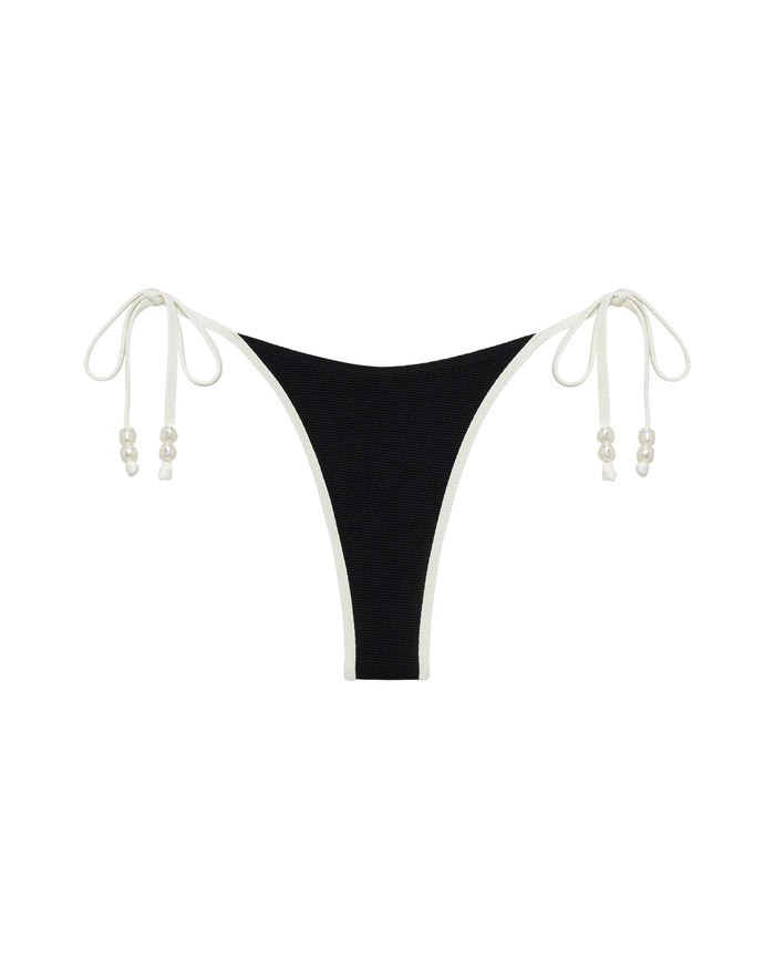 Off-model front view of the LSPACE Black-Cream Lucia Bikini Bottom showing the black fabric with cream tie-sides and pearl bead details.