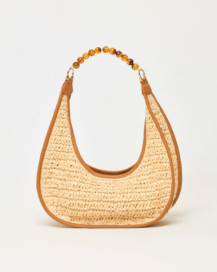 Off-model front view of the natural Mira Mar Bag, a crescent-shaped raffia bag with brown leather trim and amber bead handle.