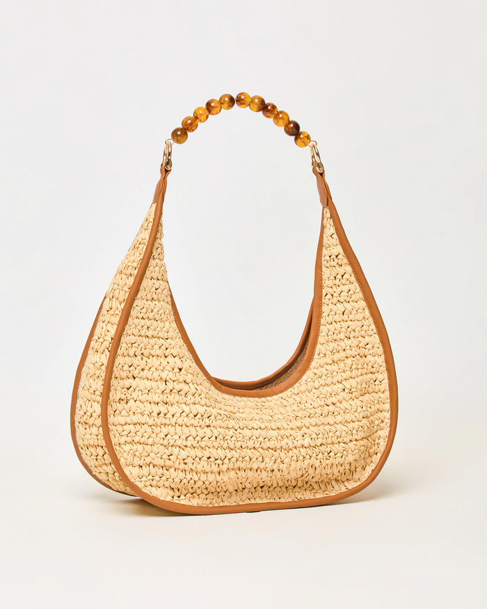 Angled side view of the natural Mira Mar Bag showing the raffia weave and brown leather trim detail.