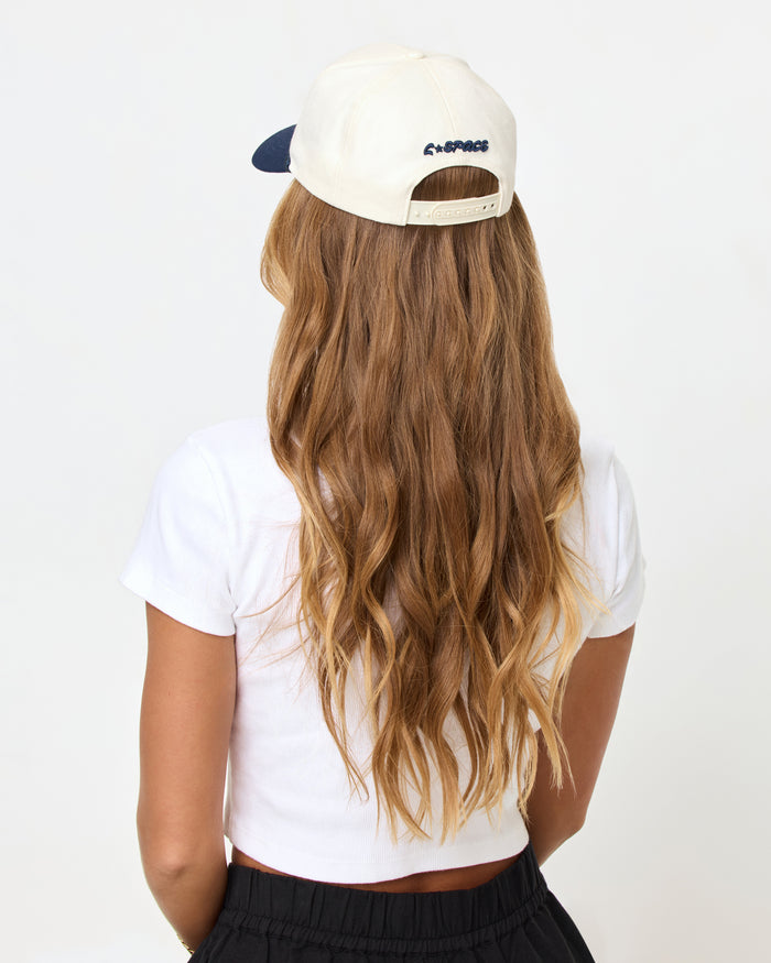 Back view of a model wearing the midnight cream Newport Hat showing the LSPACE logo.