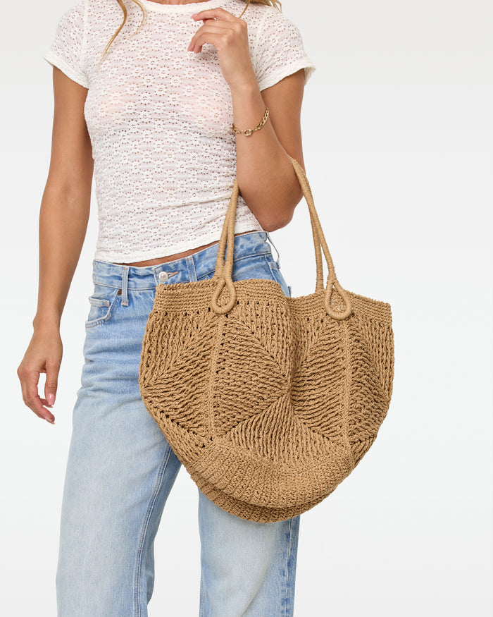 Cropped front view of a model carrying the natural Paloma Beach Tote on her shoulder.