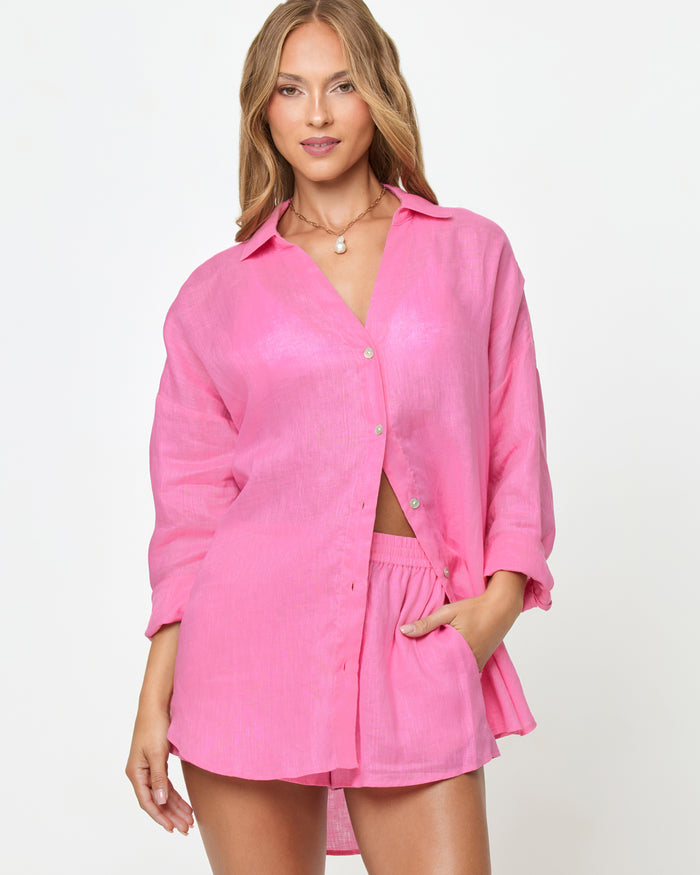 Front view of a model wearing the LSPACE Rio Tunic in hottest pink, an oversized linen button-up shirt with three-quarter sleeves, styled with the matching Rio Short.