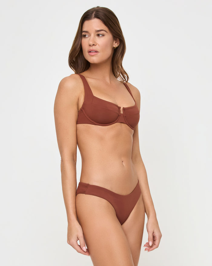Three-quarter front view of a model wearing the LSPACE Tobacco Rocky Bikini Bottom styled with a matching tobacco LSPACE underwire Mako Bikini Top with center keyhole detail.