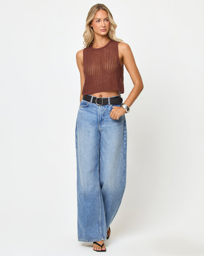 Front view of a model wearing the LSPACE Sander Top in cafe, a sleeveless crochet crop top with crew neckline, styled with wide-leg jeans and a belt.