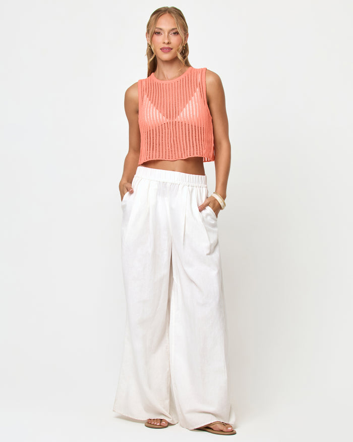 Front view of a model wearing the LSPACE Sander Top in fresh squeezed, a sleeveless crochet crop top with crew neckline, styled with white wide-leg pants.