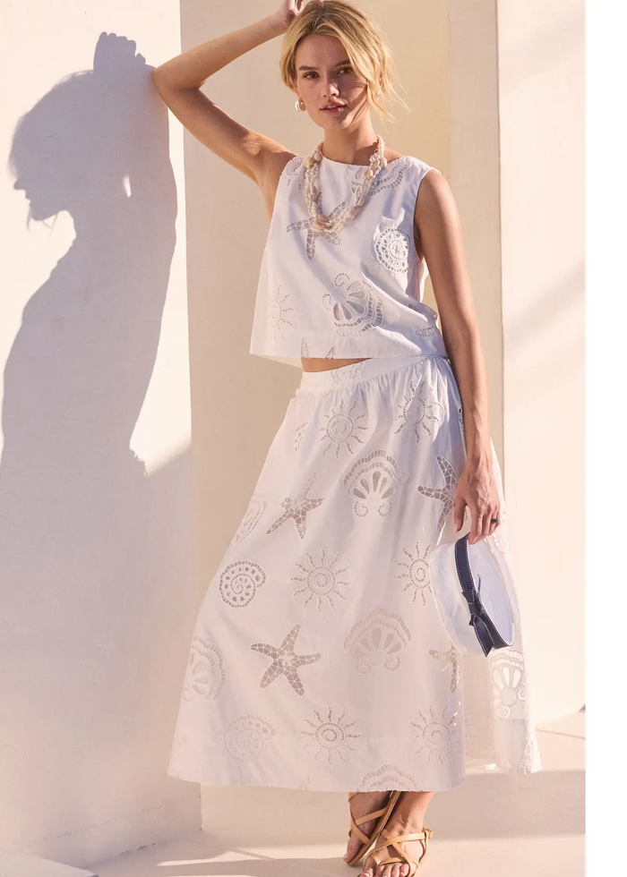 Woman wearing a light blue embroidered dress against a neutral background