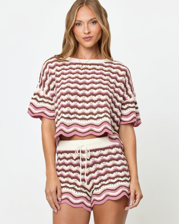 Front view on model of the LSPACE Sunchaser Top in Neapolitan, a short-sleeve crochet top in a brown, pink, and white wave pattern with scalloped hem, styled as a set with the matching Sunchaser Short.