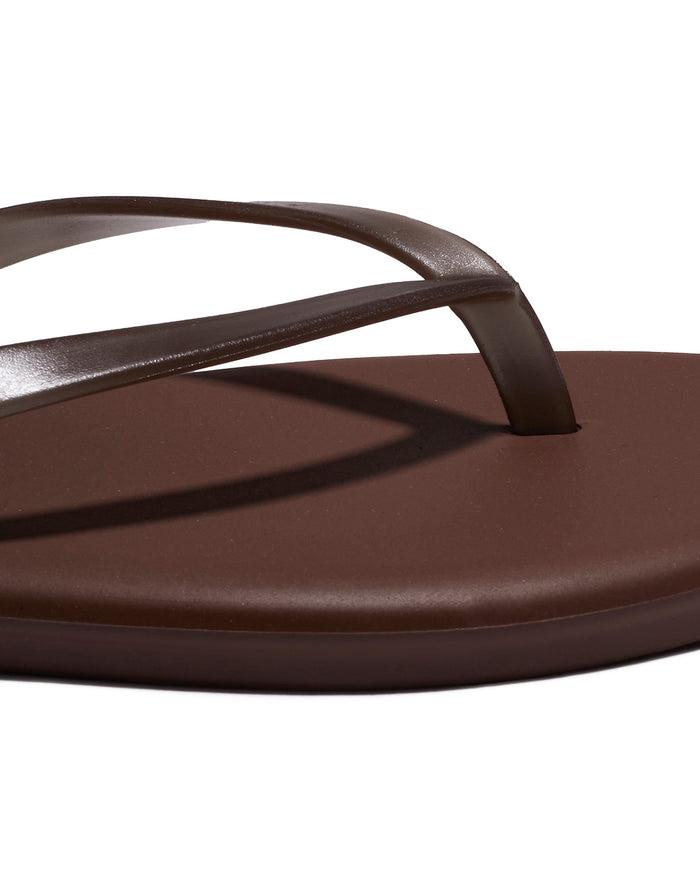 Close-up of the brown leather thong strap and footbed detail on the TKEES Aqua Sandals.