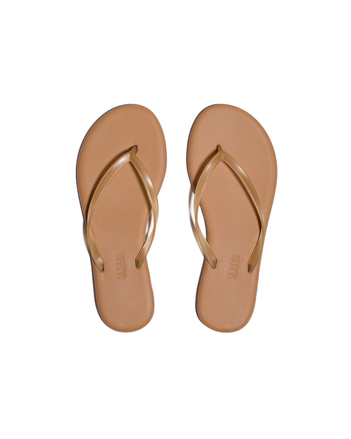 Top-down view of both tan TKEES Aqua Sandals with slim thong strap and TKEES logo on footbed.