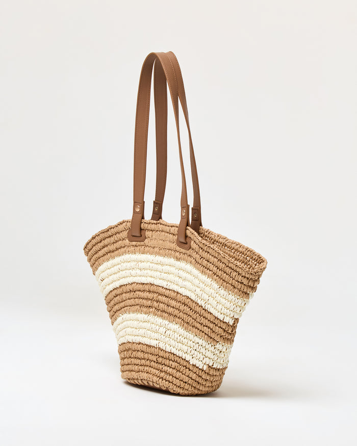 Angled side view of the natural stripe Yuli Tote showing the woven texture and brown leather strap detail.